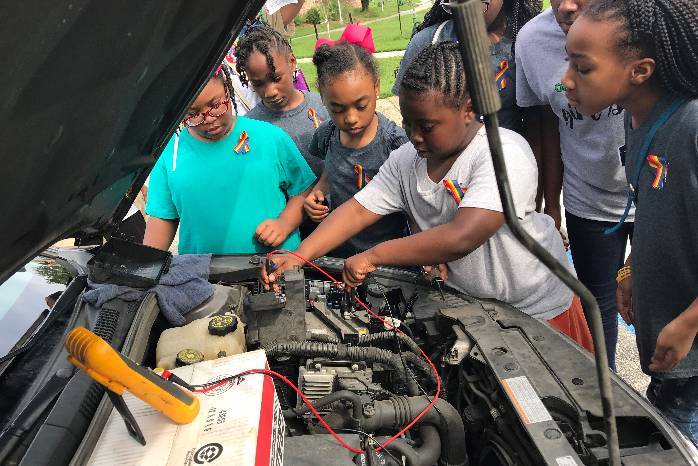 Girl Scouts work on a car