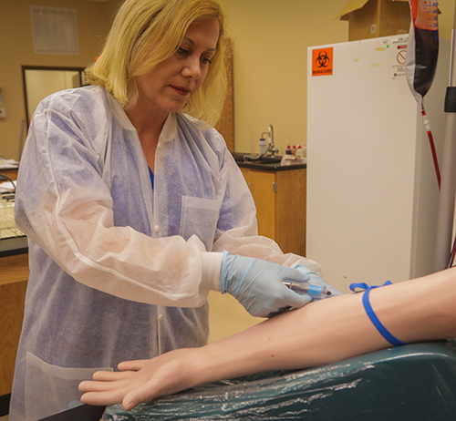 white female setting up an IV on a practice dummy