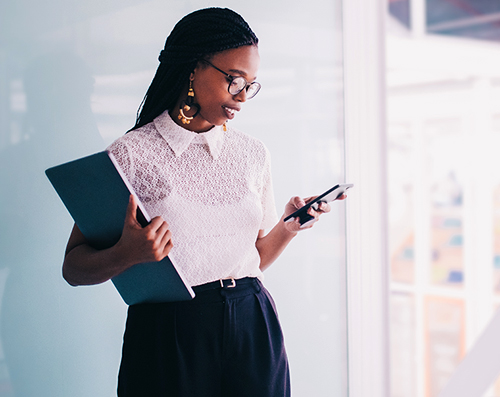 black female in an office building looking at cell phone