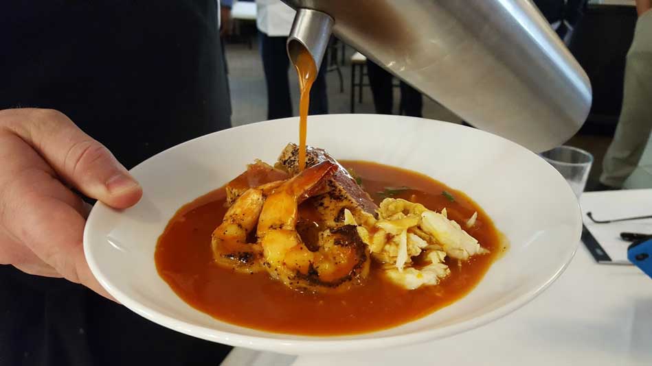 Closeup of a shrimp dish with sauce being poured on it.