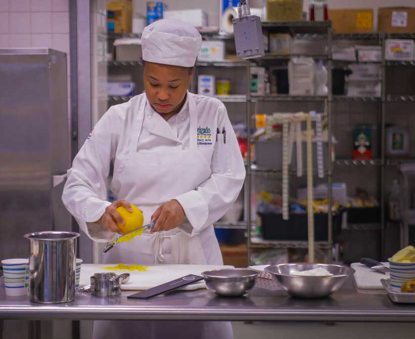 A Delgado culinary arts student zests a lemon in class.