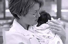 Historical black and white photo of a nurse holding an infant.