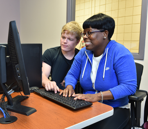 white male helping a black student on a computer
