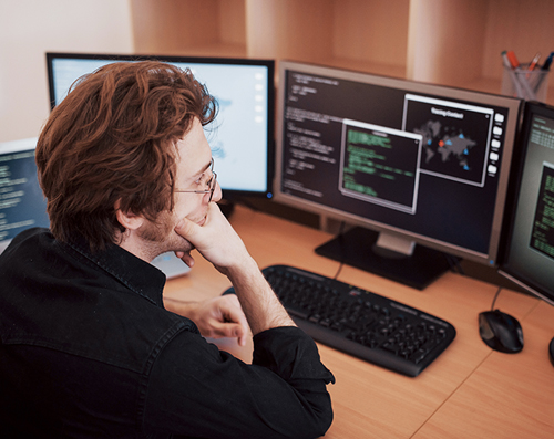 Student working on a computer with multiple screens