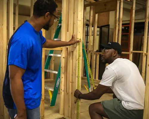 two students working on building a frame for a house