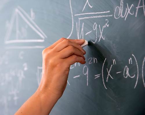 closeup of a hand at chalkboard with math equations