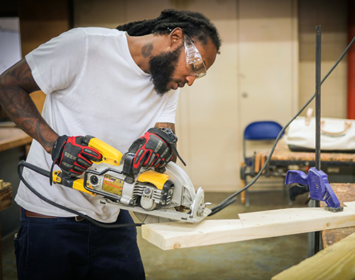 student using circular saw to cut wood