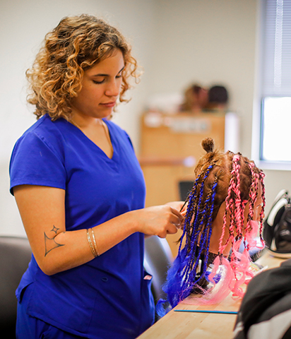Cosmetology student brading hair on a mannequin head