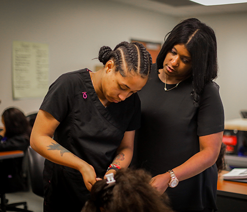 Cosmetology student brading hair on a mannequin head