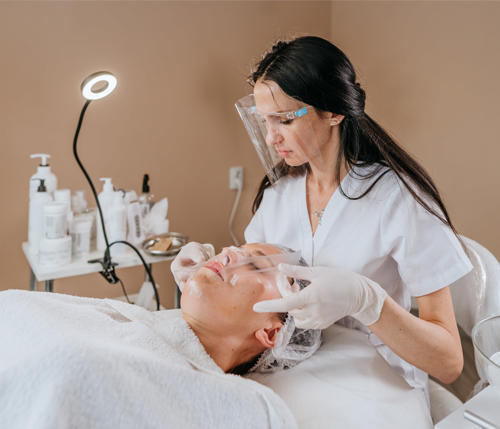 esthetician making facial cleansing procedure