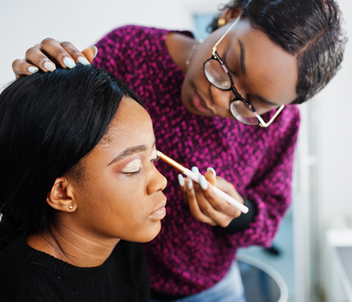 female applying lipgloss to another femaile