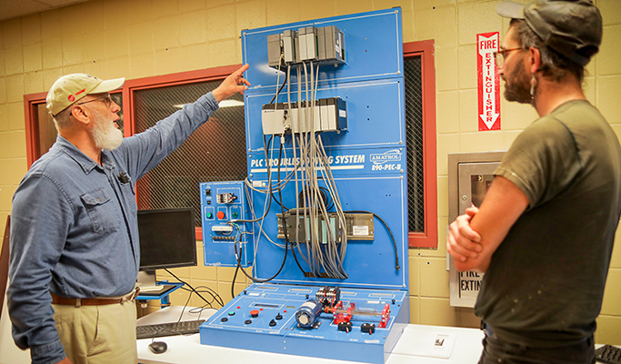 teacher showing student a PLC training simulator