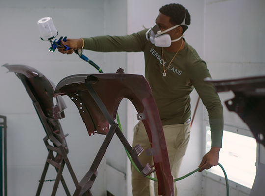 student painting a car door