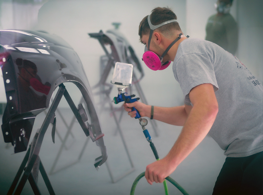 student painting a car door