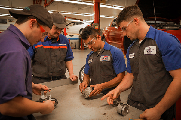 group of student looking an engine cylinders