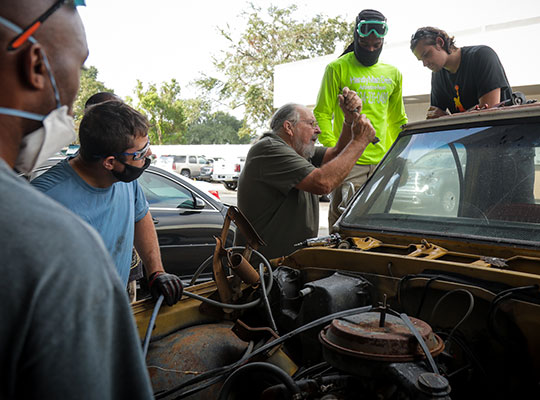 teacher showing students how to replace a window on a car