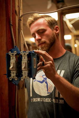 Student installing light switches on wood frame