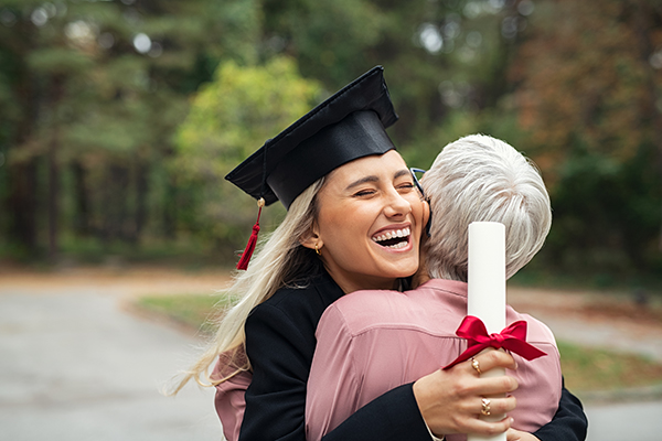 graduate in cap and gown hugging her parent