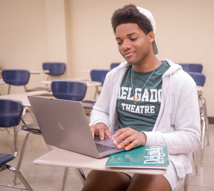 A Delgado theatre student uses his laptop in a classroom.