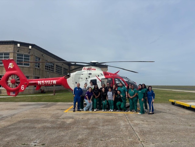 Respiratory therapy students in front of a helicpoter
