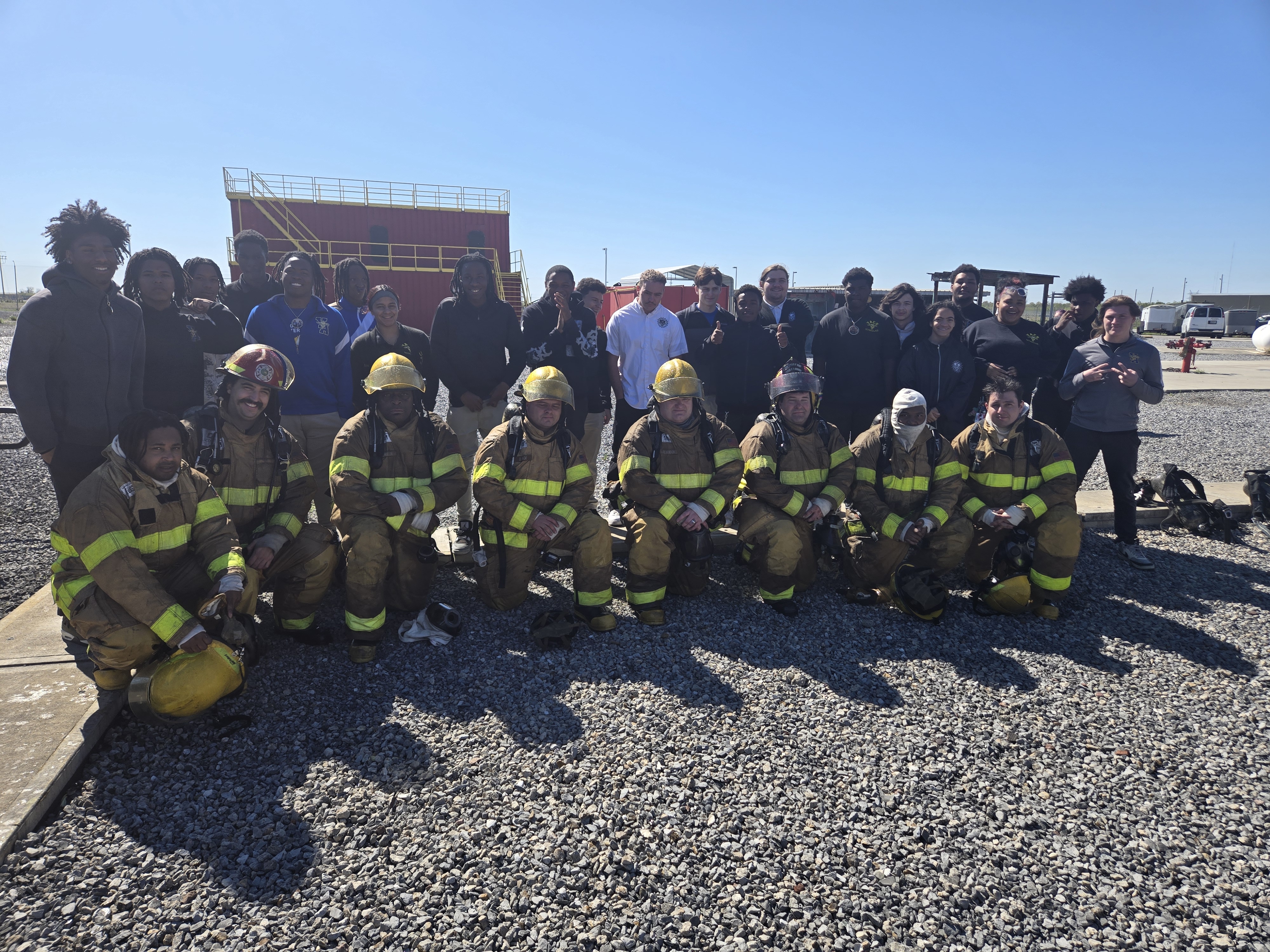 Firefighting students and charter school students pose on the fire field