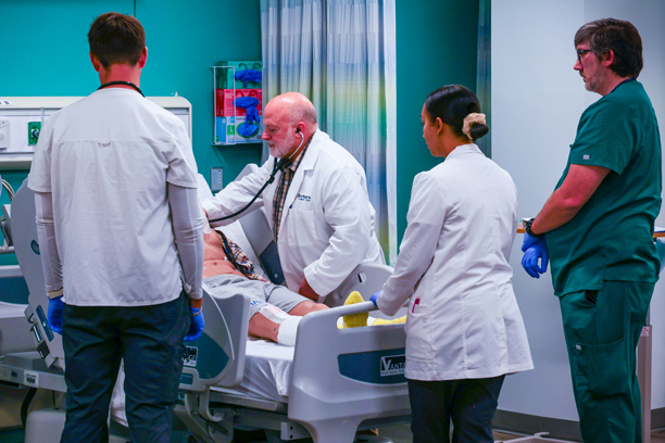 Students watching as an Ochsner doctor checks a simulated patient