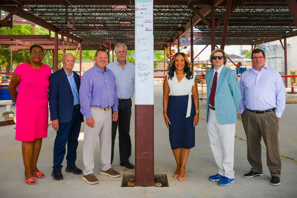 Chancellor and administrators standing next to building beam