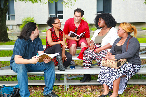 Group of students chatting and sitting on bleachers outside