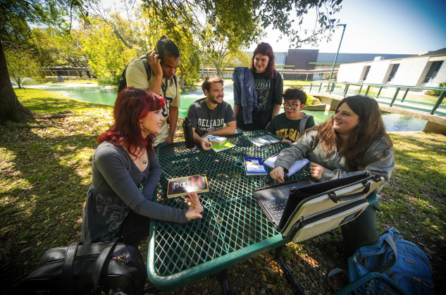 group of students sitting at an outdoor table on campus