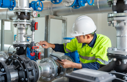 maintence worker looking at a guage on an industrial pump