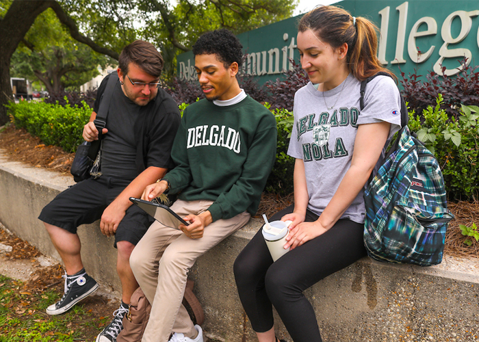students in front of building 2 looking at an ipad