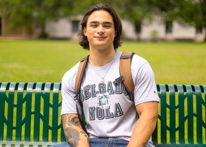 male student sitting on a bench on campus